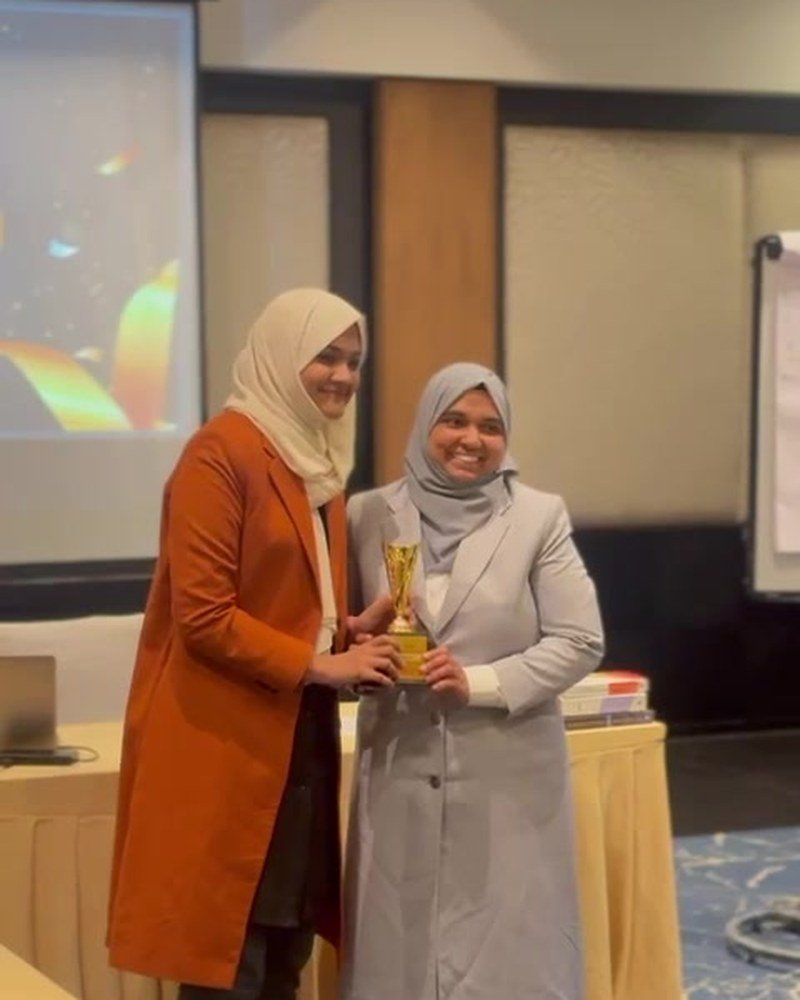 Rabeeba Vellangara accepting a trophy from a fellow trainer at an awards ceremony