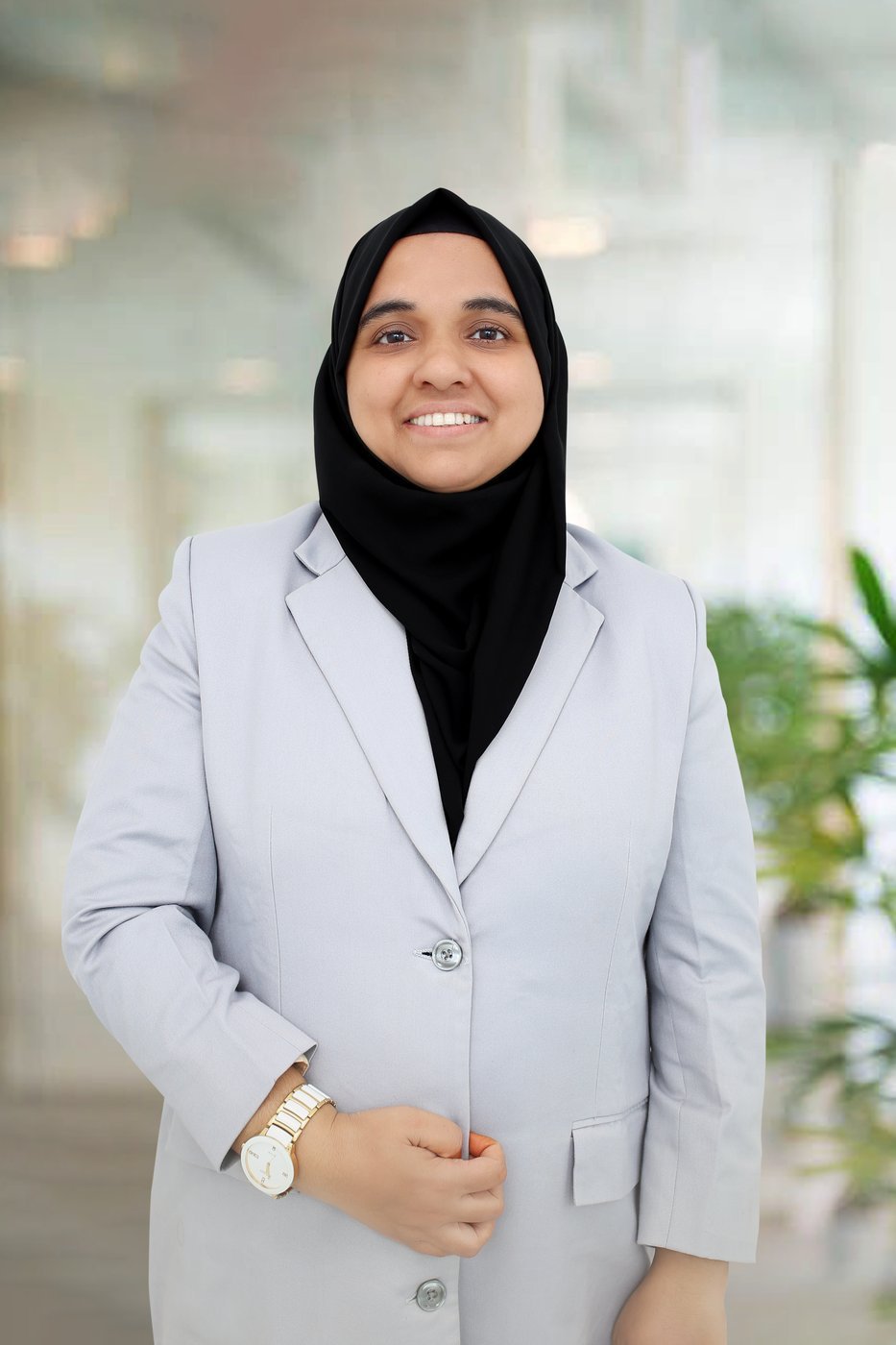 Rabeeba Vellangara in a grey blazer standing beside an office window